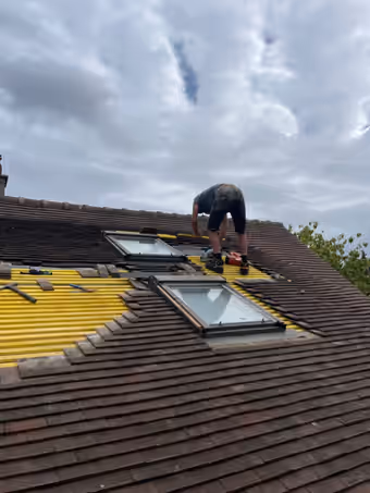 Deux fenêtres de toit reposées sur des liteaux neufs, tuiles mécaniques en cours de remise en place